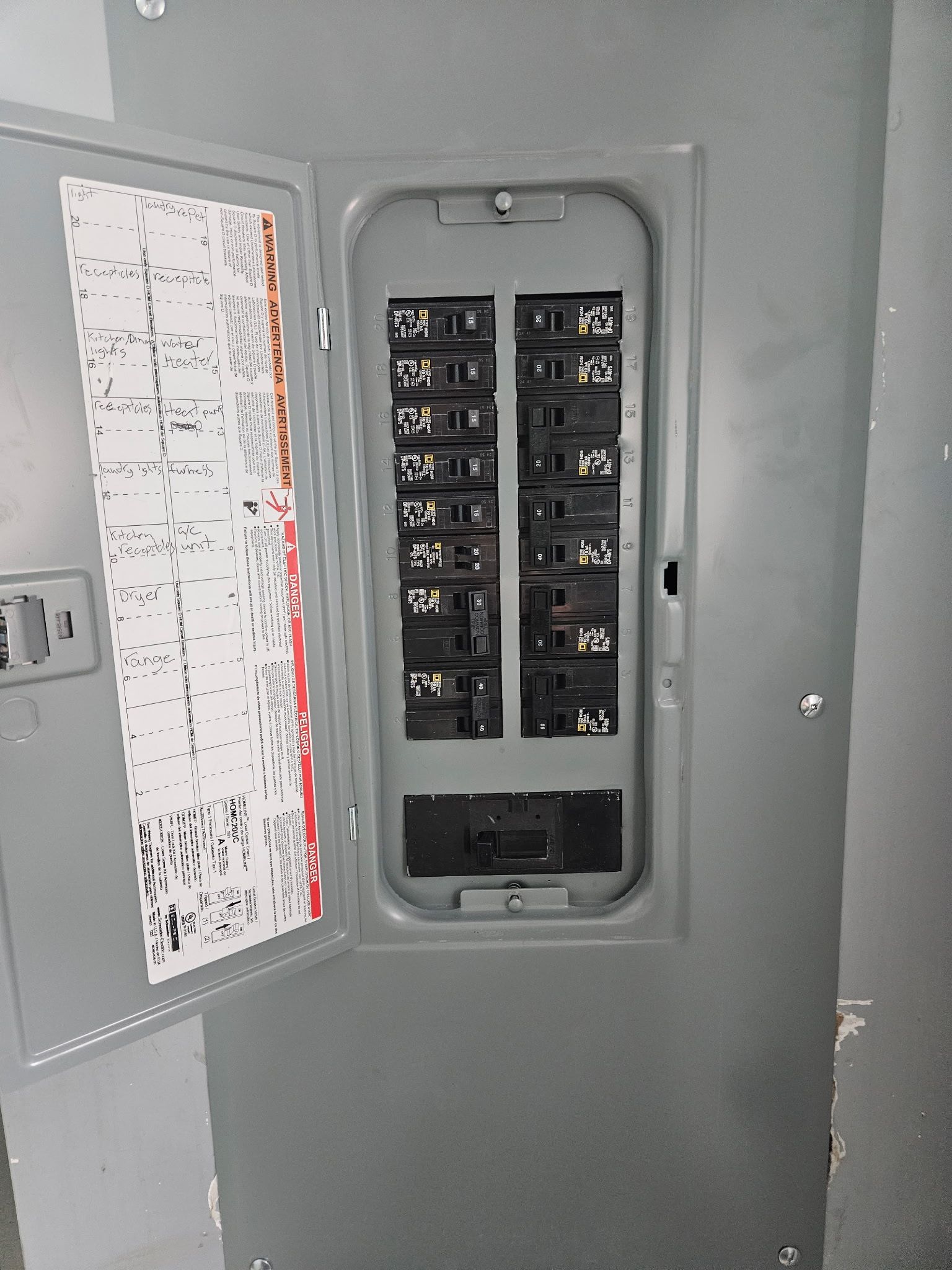 Open Square D Homeline breaker panel with a hand-written circuit directory covering kitchen, laundry, range, dryer, water heater and heat pump circuits